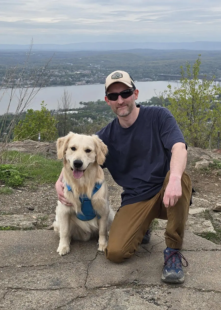 Scott, founder of Hudson Valley Botanicals, kneeling beside his dog at a mountain overlook